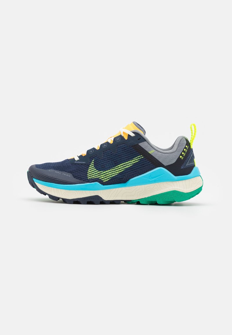 Chaussure de course bleu marine et gris avec des lacets jaune néon, logo swoosh vert et jaune, semelle bleue et blanche, et détail de la bande de roulement vert.