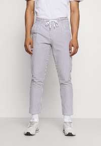 Proužkované lehké kalhoty s elastickým pasem a stahovací šňůrkou, svislé modrobílé pruhy, zúžený střih a boční kapsy.