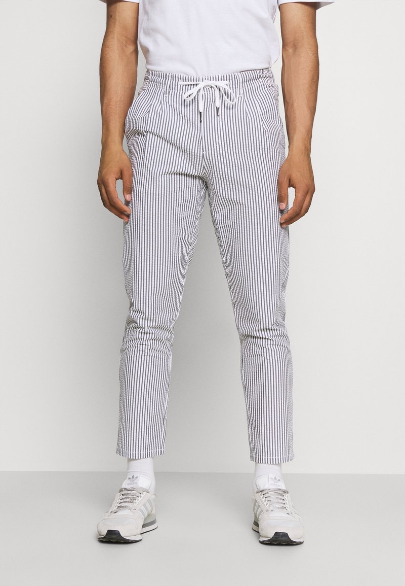 Proužkované lehké kalhoty s elastickým pasem a stahovací šňůrkou, svislé modrobílé pruhy, zúžený střih a boční kapsy.