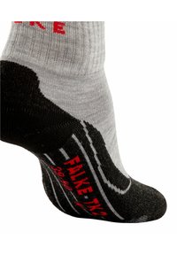 Szary skarpet z czarnym palcem i piętą. Ma czerwony nadruk z napisem „FAKE” i białe paski. Wykonana z prążkowanej tkaniny o miękkiej fakturze.