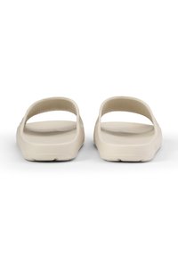 Lyse beige slip-on sandaler med en glat overflade, åben ryg og to brede stropper for en sikker pasform. Sålens mønster er minimalt.
