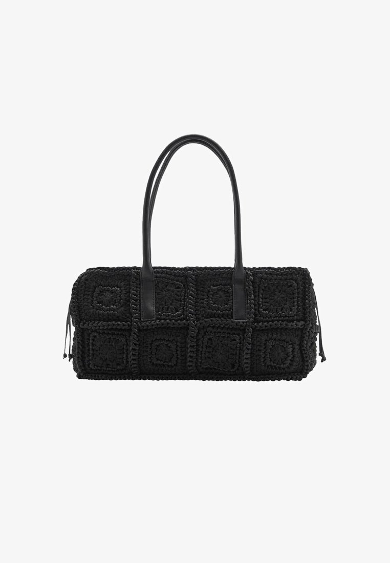 Bolso de mano de crochet negro con forma rectangular, que presenta cuadrados texturizados y asas de cuero lisas. Los acentos incluyen borlas en un lado.