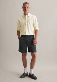 Lichtgele gestreepte button-up shirt, marineblauwe shorts, witte sokken en zwarte instappers. Het shirt heeft een klassieke kraag en een normale pasvorm.