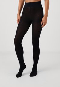 Black opaque tights with a smooth texture, high waistband, and no patterns; fitted to the legs and feet with a seamless design.