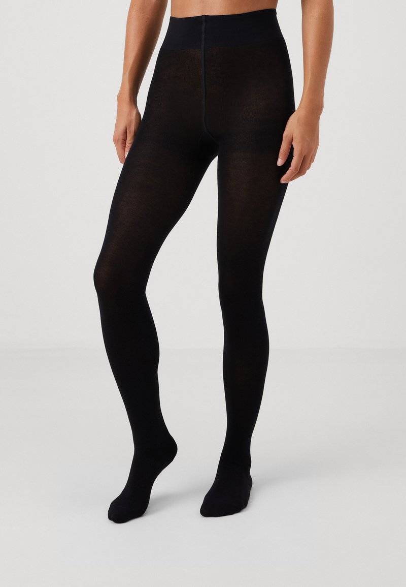 Black opaque tights with a smooth texture, high waistband, and no patterns; fitted to the legs and feet with a seamless design.