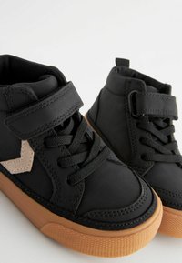 Czarne sneakersy typu high-top z teksturowaną powierzchnią, z beżowym zygzakiem, czarnymi sznurówkami i gumową, brązową podeszwą. W zestawie pasek na rzep.
