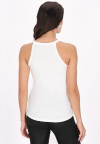 Fehér, ujjatlan trikó kerek nyakkivágással és ívelt aljjal, puha, könnyű anyagból készült, racerback kialakítással.