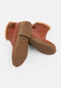 Braune Leder-Stiefeletten mit einem Futter aus Kunstfell, Schnallenakzent und strukturiertem Gummisohlen. Runde Zehenform und weiches, warmes Innenleben.