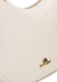 Witte leren handtas met een gestructureerd oppervlak, gebogen vorm en gouden hardware met het WITTCHEN-logo onderaan.