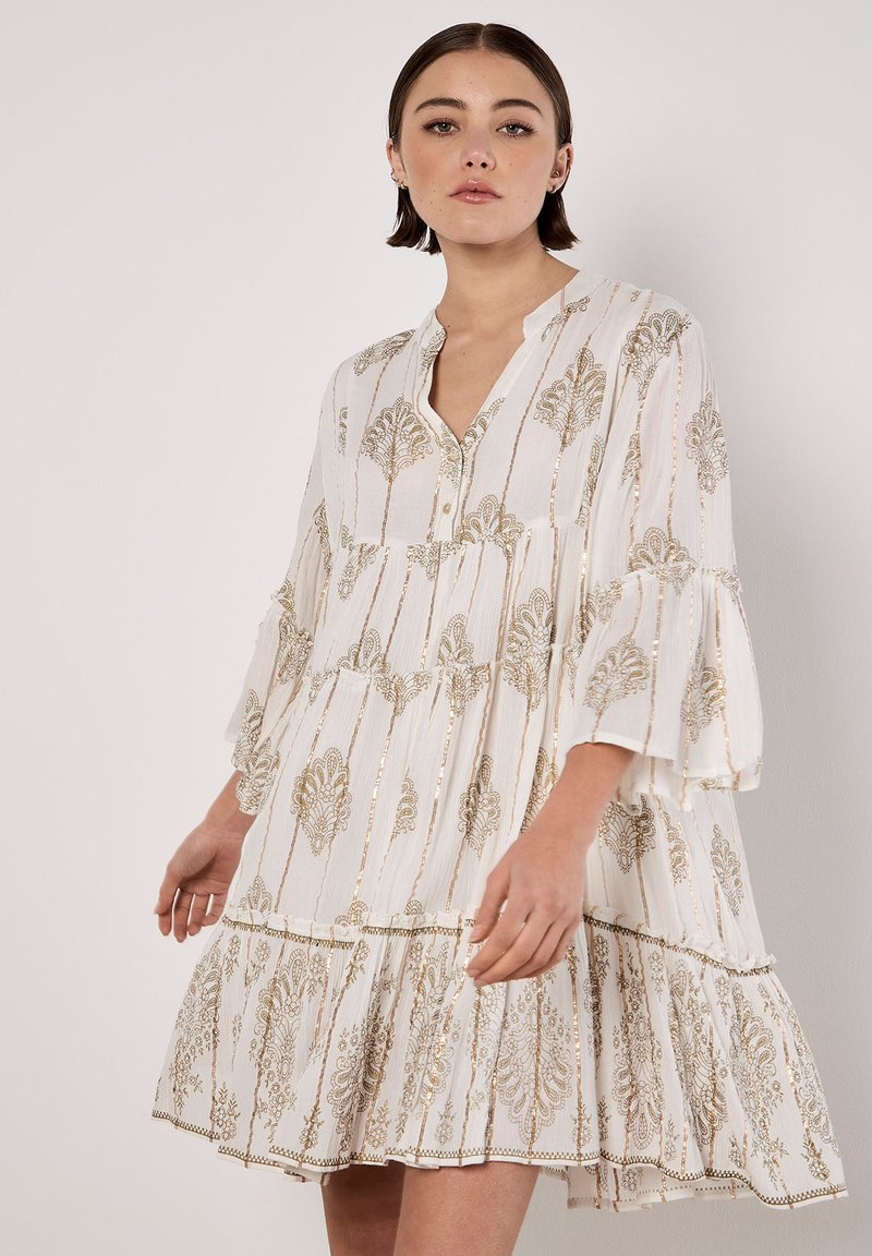 Weißes Kleid mit goldenen detaillierten Mustern, plissierter Textur, Knopfleiste vorne und Glockenärmeln. Der ausgestellte Saum trägt zur Gestaltung bei.