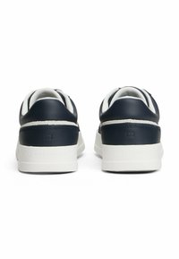 Granatowe skórzane sneakersy z białymi detalami, niskoprofilowy design i wyściełany kołnierz. Posiadają wytłoczone logo na pięcie oraz teksturowaną podeszwę.