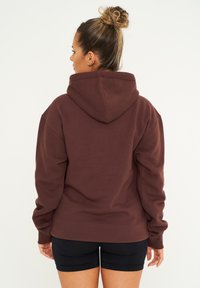 Braun kapuzenpullover aus einem weichen, strukturierten Stoff. Verfügt über eine lässige Passform mit gerippten Bündchen und einer Kängurutasche.
