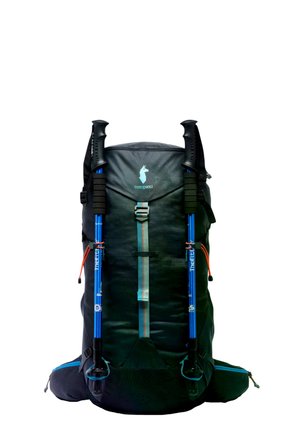 Mochila de senderismo negra Cotopaxi con bastones de trekking azules adjuntos, asegurados con correas frontales, aislada sobre fondo blanco.