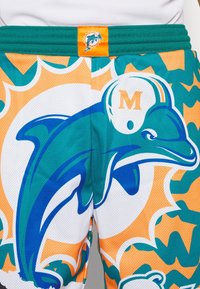 Shorts a rete verdi e arancioni con una grande grafica di un delfino, un motivo esagonale e un logo del team ricamato in vita.
