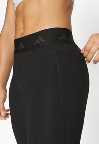 Leggings deportivos negros con una amplia cinturilla elástica que presenta sutiles acentos de logotipo negro, textura suave y un diseño ajustado.
