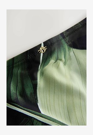 Zeleno-čierna vzorovaná tkanina s hladkou textúrou; obsahuje detail zlatého akcentu na páse; tenké, vertikálne línie sú súčasťou dizajnu.