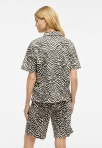 Kortsleeve skjorte og shorts sett i beige og mørkebrun zebra mønster. Mykt stoff, avslappet passform, og subtile teksturdetaljer gjennom hele.