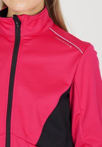 Fitted, zip-up jacket in bright pink with black accents. Soft, stretchy fabric with contrast stitching and logo detail on shoulder.