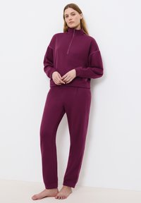 Burgundy, zip-halströja med långa ärmar, matchad med tapered sweatpants. Mjukt material och avslappnad passform med minimala sömmar.