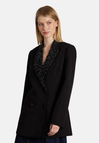 Blazer nero doppiopetto con revers in perline nere testurizzate, colletto in satin liscio, due bottoni e tasche laterali.