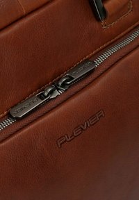 Borsa in pelle marrone con superficie texture, dotata di una cerniera in argento e un tirante metallico incisa con "PLEVIER."