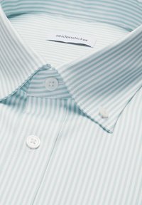 Chemise à rayures vert clair et blanc avec col boutonné et boutons blancs, étiquette de marque "seidensticker" visible à l'intérieur du col.