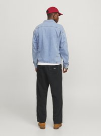 Lichtblauwe denimjack met een comfortabele pasvorm; donkere broek; rode pet; bruine laarzen; opvallende stiksels en pocketdetails aan de achterkant.