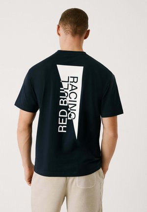Camiseta de algodón azul marino con un gran gráfico diagonal blanco que presenta el texto "RED BULL RACING" en la parte posterior. Manga corta y cuello redondo.