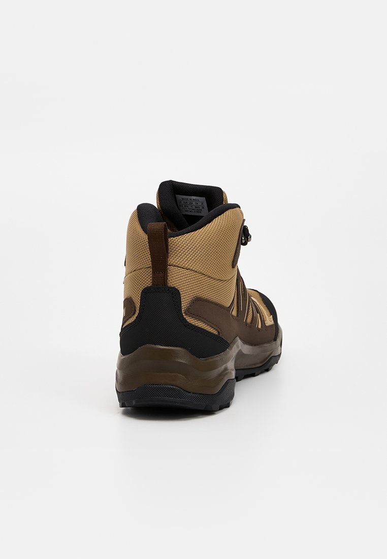 Botas de senderismo en marrón y negro, con un upper de tela texturizada, refuerzo en el talón y suela de goma para mayor tracción. Mecanismo de cierre ajustable.