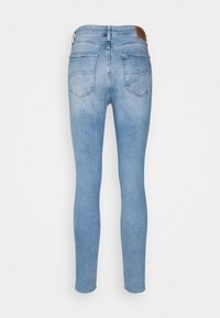 Jeans ajustados de color azul claro con una textura suave, cinco bolsillos y una etiqueta de cuero con la marca en la cintura. Diseño entallado desde la cintura hasta el tobillo.