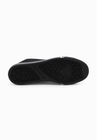 Suela de zapatilla negra con un intrincado patrón de goma que presenta un diseño geométrico y la marca "ON" visible cerca del talón.