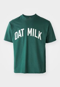 Green cotton t-shirt featuring white curved text "DAT MILK." Short sleeves and classic crew neck design with a relaxed fit.