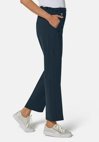 Marineblauwe broek met een rechte snit, elastische taille en zijzakken, gecombineerd met witte veterschoenen met een gestructureerde afwerking.