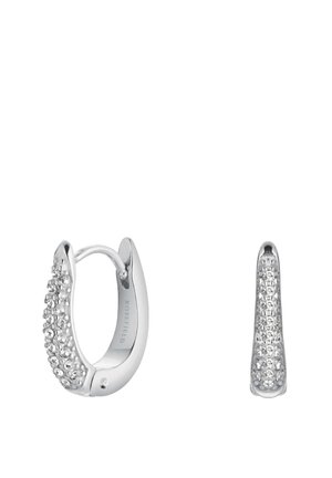 Náušnice typu huggie v barvě stříbra s hladkým povrchem, které mají řadu čirých krystalů na přední straně a elegantní, prodloužený design.