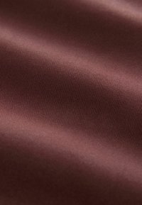 Tissu bourgogne profond avec une texture lisse et brillante et de fines lignes côtelées. Le matériau semble doux et léger, adapté à diverses applications.
