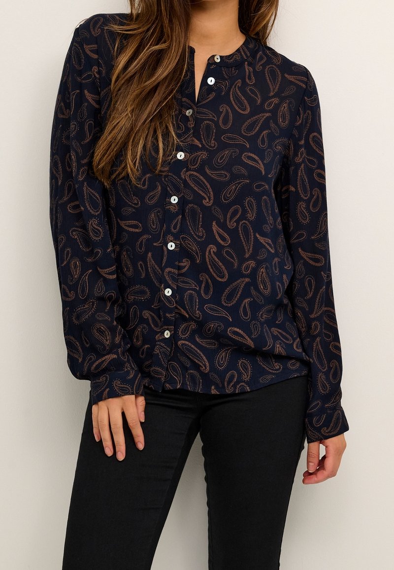 Námořnická button-up blůza s paisley vzorem v hnědé barvě, dlouhé rukávy, kulatý výstřih a volný střih. Vyrobena z lehkého materiálu.