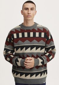 Knit sweater featuring a geometric pattern in maroon, gray, black, and cream. Ribbed crew neckline and cuffs, relaxed fit.