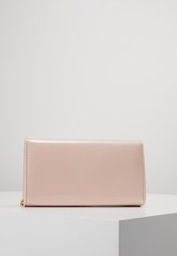 Obdélníková peněženka z růžové lakované kůže s hladkou texturou, vybavená zipovým uzávěrem a jemným prošíváním podél hran.