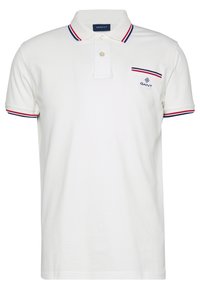 Biała koszulka polo wykonana z bawełny, z dwiema guzikami, niebieskimi i czerwonymi paskami na kołnierzyku i rękawach oraz małym logo na piersi.