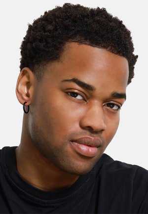Black hoop earring worn on the left ear, close-up of facial features, curly dark hair, smooth skin, wearing a black shirt.
