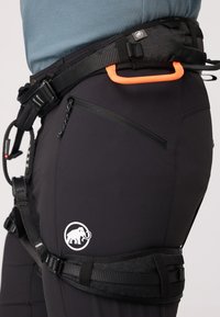 Schwarzes Klettergeschirr mit verstellbaren Riemen, orangefarbener Karabinerhalter, Logo-Patch und Reißverschlusstasche zur sicheren Aufbewahrung von Ausrüstung.