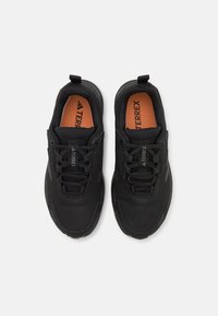 Czarne buty sportowe z teksturowaną cholewką, sznurowane, z pomarańczowymi wkładkami, z logo "Terrex" na języku.