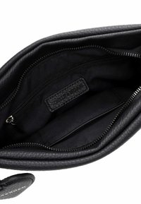Black leather bag interior with smooth texture, featuring a zip pocket and fabric lining. Notable brand label in a woven design.