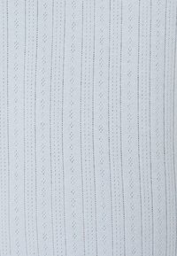 Tecido branco de malha com riscas verticais e pequenos padrões de diamante, superfície texturizada e detalhes de ponto consistentes por toda a extensão.