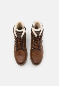 Bruine leren enkelboots met faux fur voering, vetersluiting, contrasterende stiksels en een gestructureerd oppervlak. Rubberen zool met lichte grip.