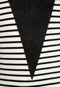 Černobílá pruhovaná látka se strukturovaným černým trojúhelníkovým tvarem uprostřed. Vyznačuje se lesklým, hmatovým povrchem kontrastujícím s pruhy.