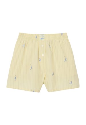 Caleçons boxers jaunes rayés avec des illustrations de joueurs de tennis en bleu et une braguette à boutons sous une ceinture élastique.