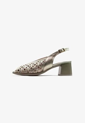 Zapato de mujer dorado metálico de punta abierta con tira trasera, patrón geométrico recortado y tacón en bloque sobre fondo blanco.