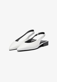 Valkoiset nahka slingback-kengät, joissa on terävä kärki, tasainen musta korko ja avoimet sivut, joissa on sileä pinta ja minimaalinen varustus.
