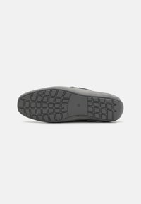 Semelle de chaussure en caoutchouc noir avec un motif de grip texturé, un bout rond et des bords lisses. Conception simple sans marque ni accents visibles.